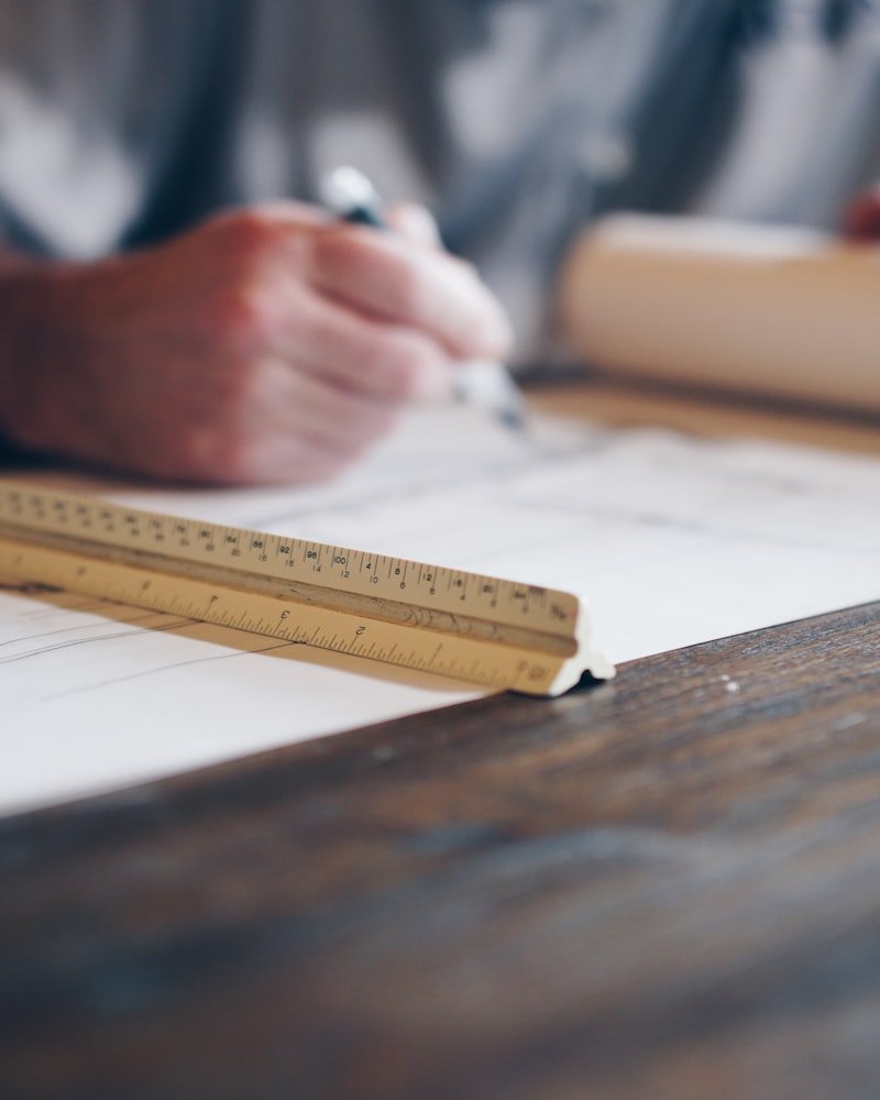Architect drafting residential drawings with scale rule and drafting tools